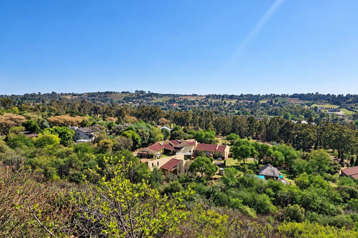 An elevated aerial view of the property estate, showcasing the main residence, swimming pool, and surrounding lush green landscape.