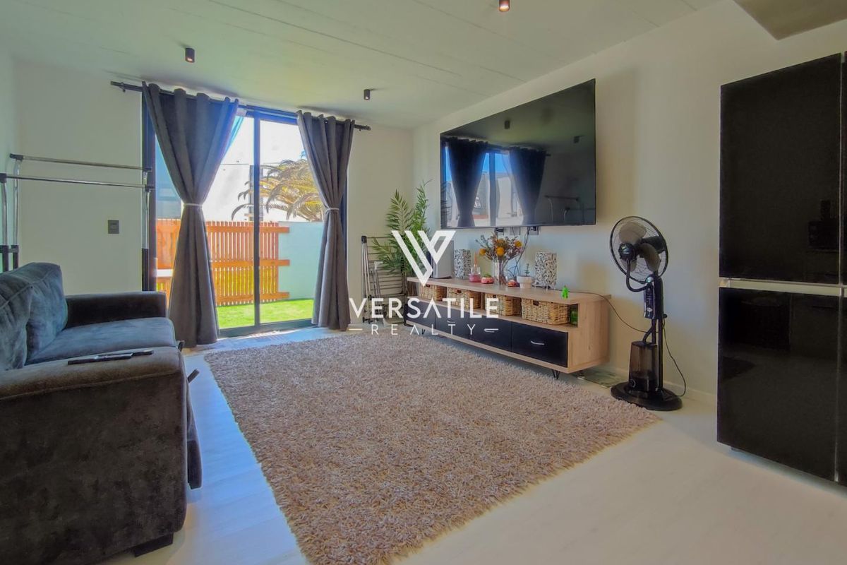 A bright living room featuring modern laminate flooring, recessed ceiling lighting, and a large sliding glass door providing direct access to the outdoor area.