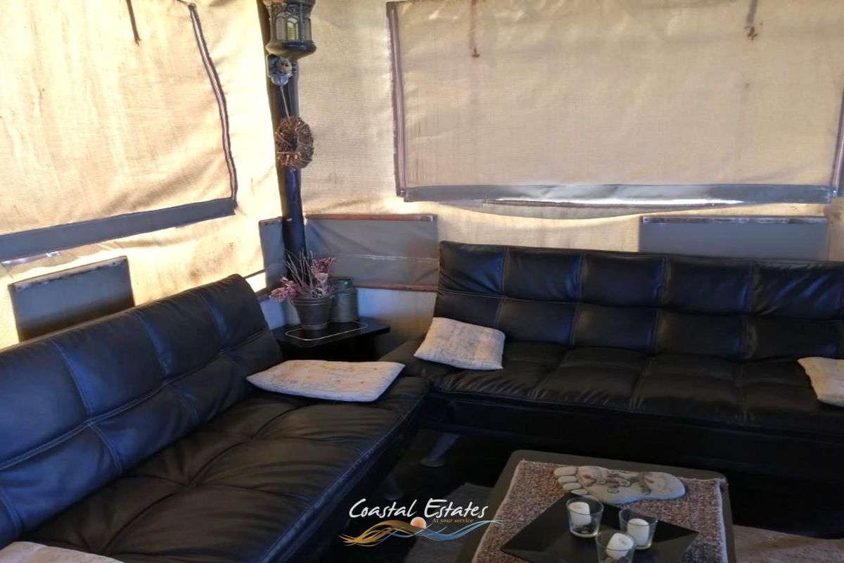 A casual living area featuring canvas wall panels and roll-up blinds, creating a relaxed, tent-style interior atmosphere.