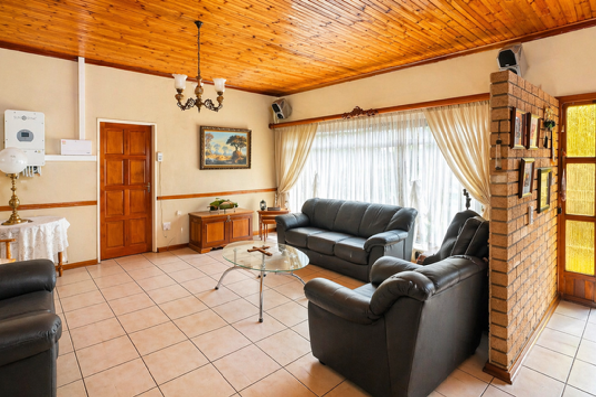 Spacious living room featuring tiled flooring, a timber-clad ceiling, and a decorative brick partition wall leading to the entrance.