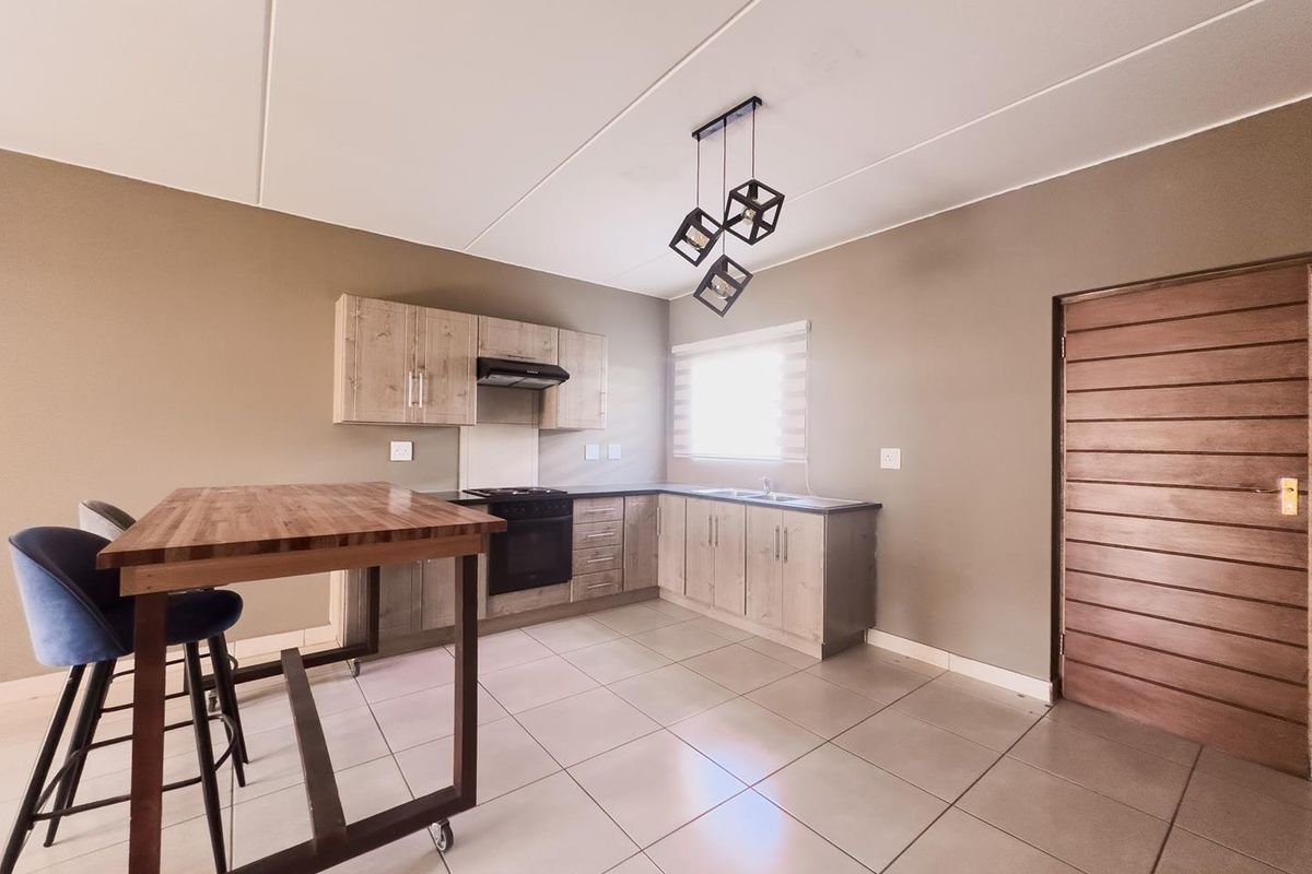 Modern kitchen featuring light wood-grain cabinetry, built-in oven with extractor fan, tiled flooring, and a functional breakfast island.