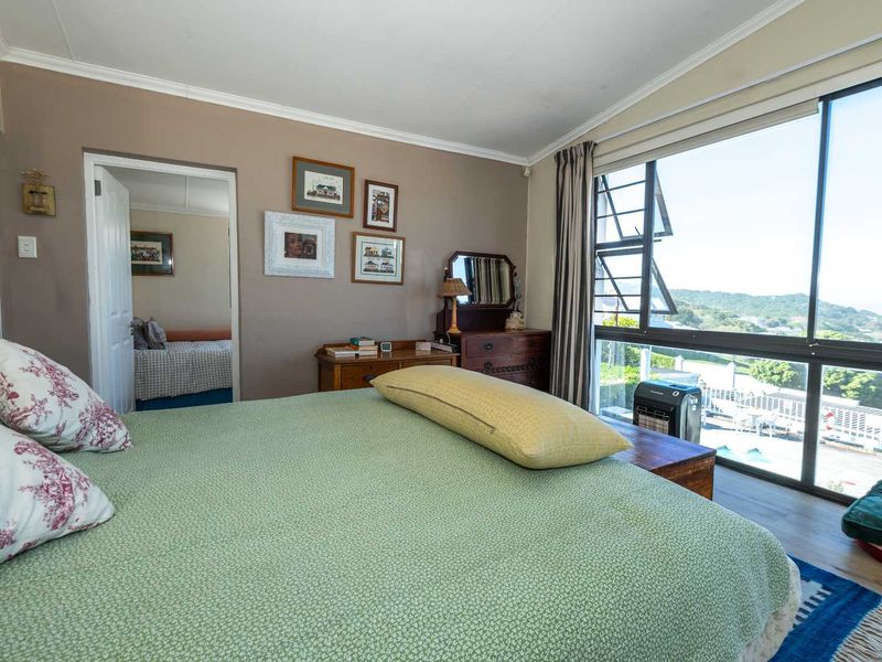 A well-lit bedroom featuring large windows with scenic views, neutral wall tones, and direct access to an adjoining room.