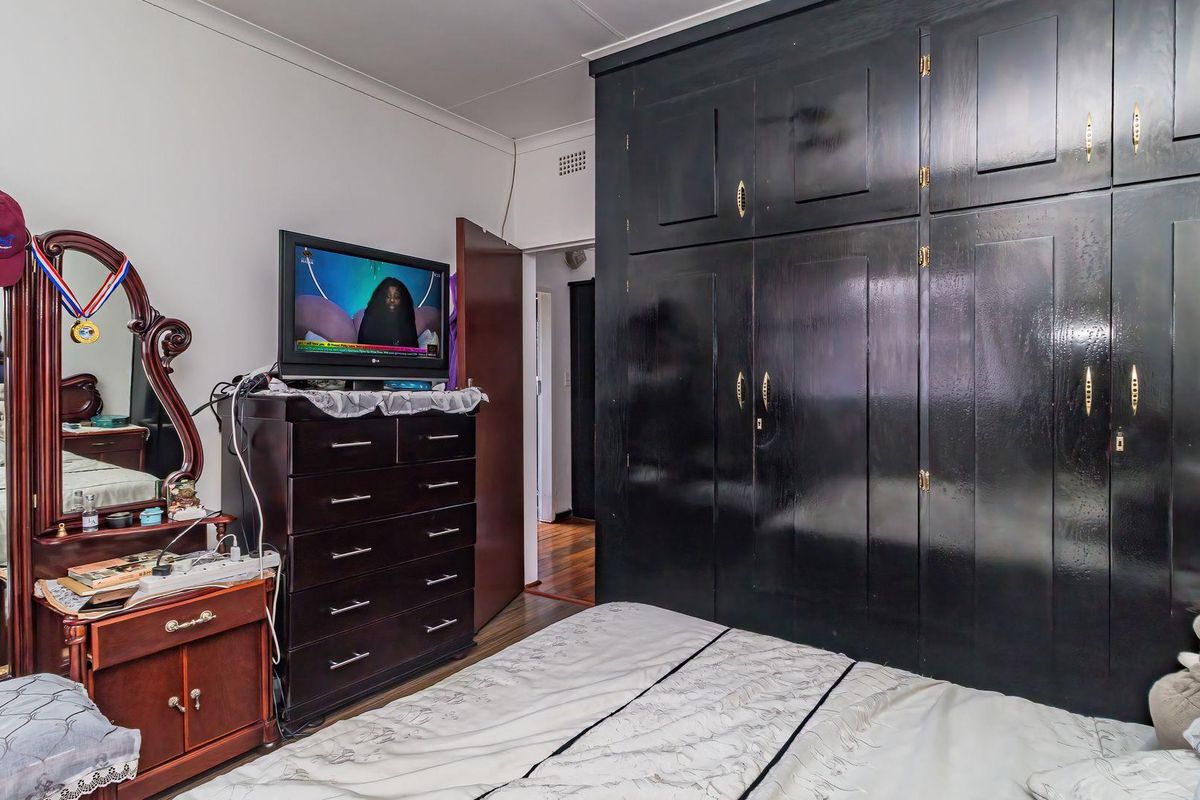 A bedroom featuring dark built-in cupboards and hardwood flooring, offering a functional space with potential for modern updates.