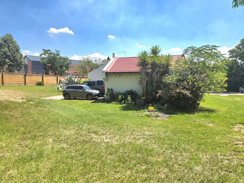 Rear view of the property showing the tiled roof structure, concrete driveway, and surrounding garden area on a small holding.