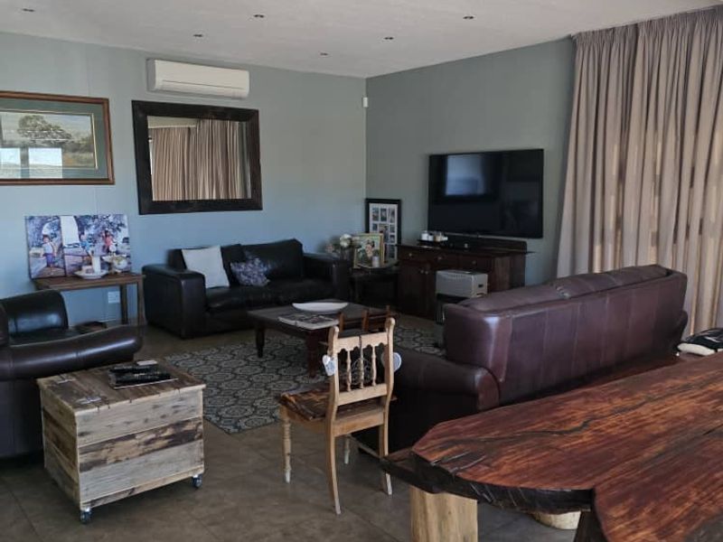 Spacious living area featuring tiled flooring, recessed downlighting, and a wall-mounted split-system air conditioning unit.