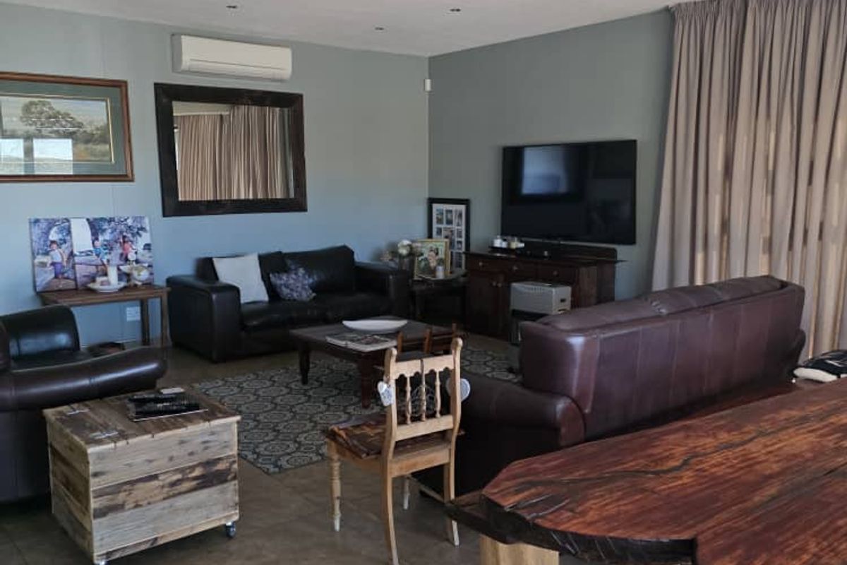 Spacious living area featuring tiled flooring, recessed downlighting, and a wall-mounted split-system air conditioning unit.