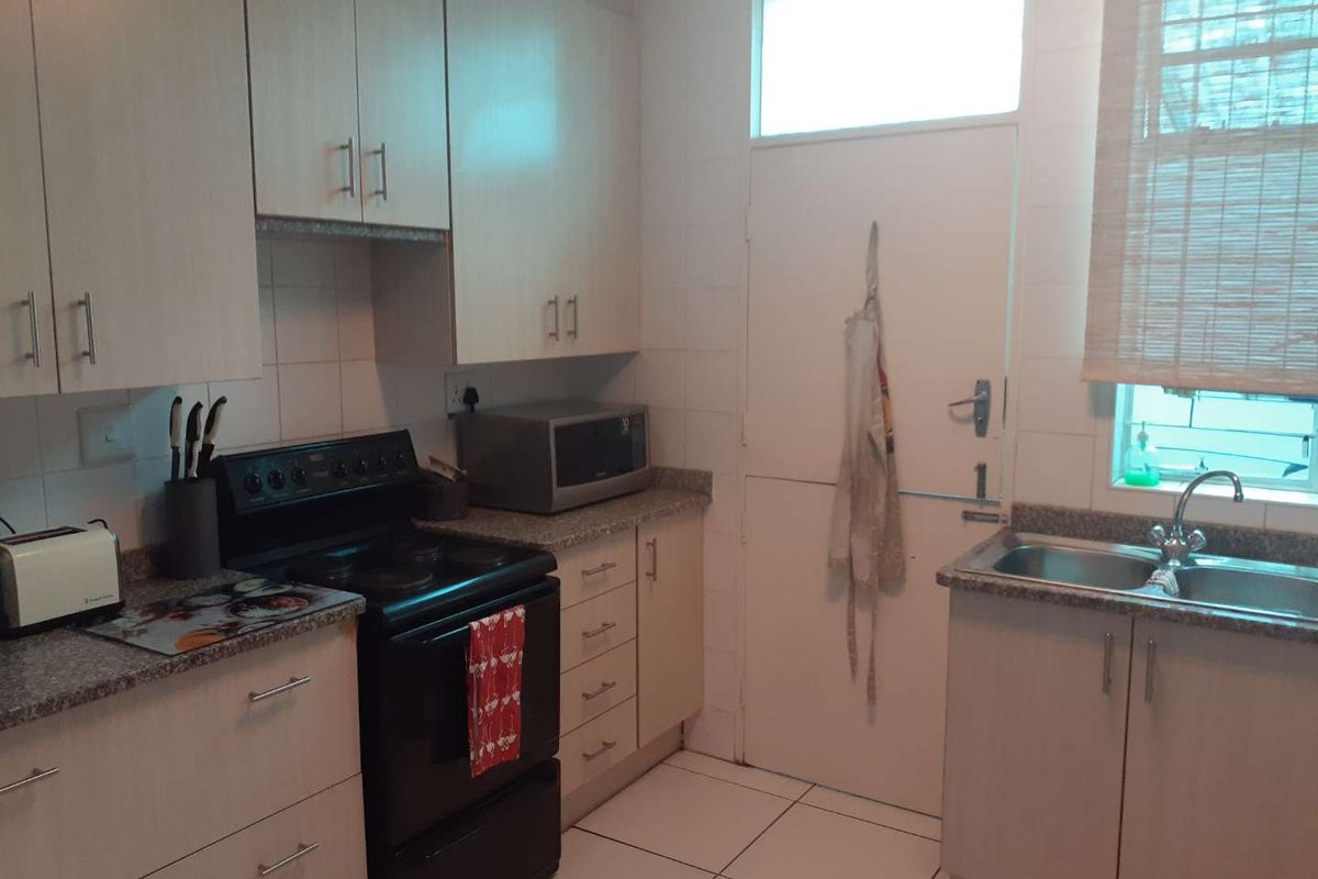 A functional kitchen featuring light-toned cabinetry, granite-look laminate countertops, a double bowl sink, and tiled flooring with a practical layout.