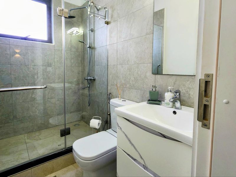 Modern bathroom featuring a glass-enclosed shower, contemporary vanity with basin, and neutral wall tiling.