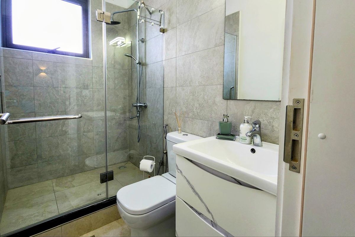 Modern bathroom featuring a glass-enclosed shower, contemporary vanity with basin, and neutral wall tiling.