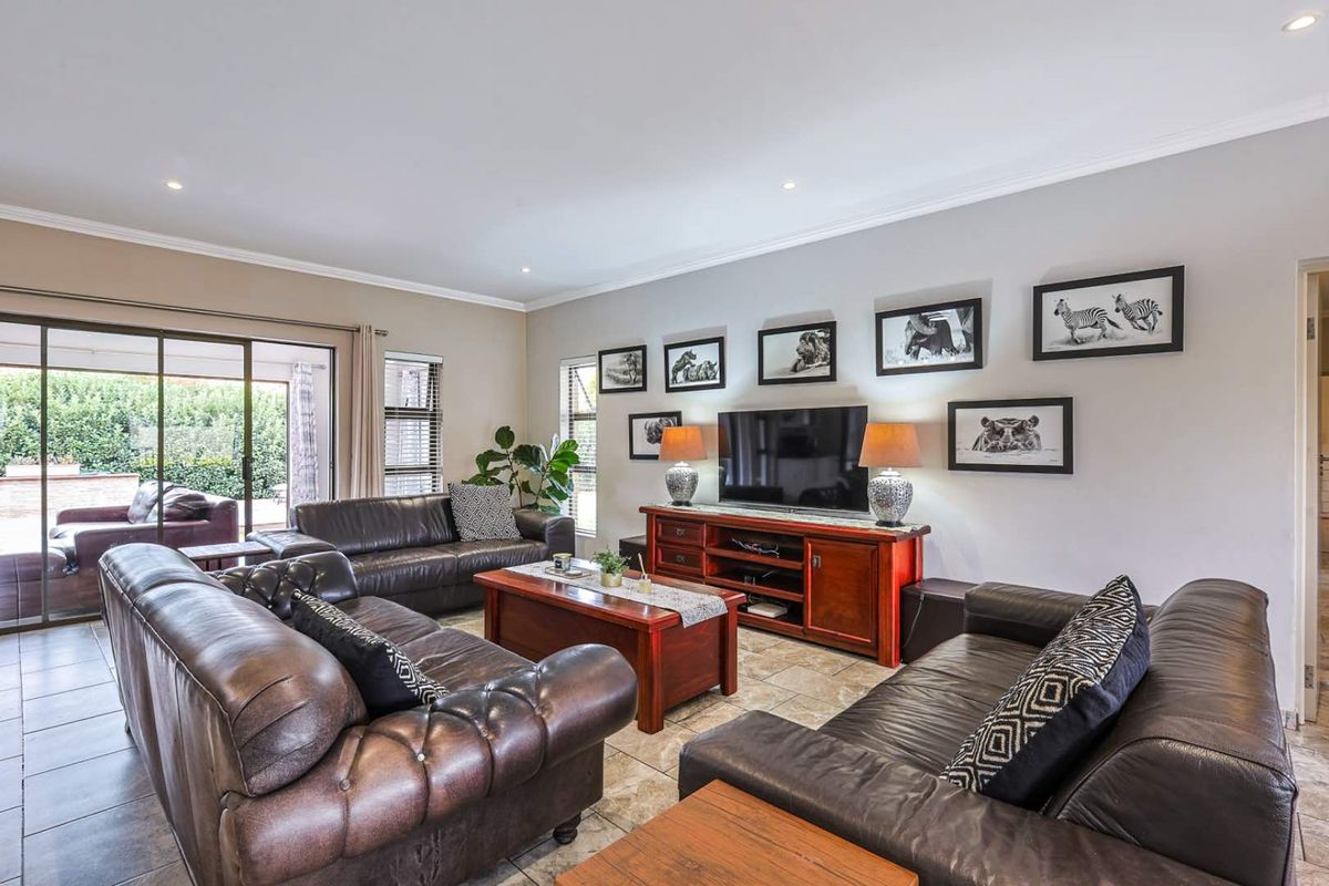 Spacious living room featuring tiled flooring, recessed downlighting, and large sliding glass doors providing direct access to the outdoor patio area.