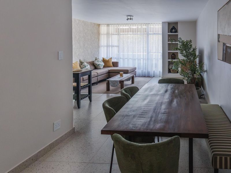 Spacious open-plan living and dining area featuring terrazzo flooring, built-in shelving, and large sliding glass doors leading to a balcony.