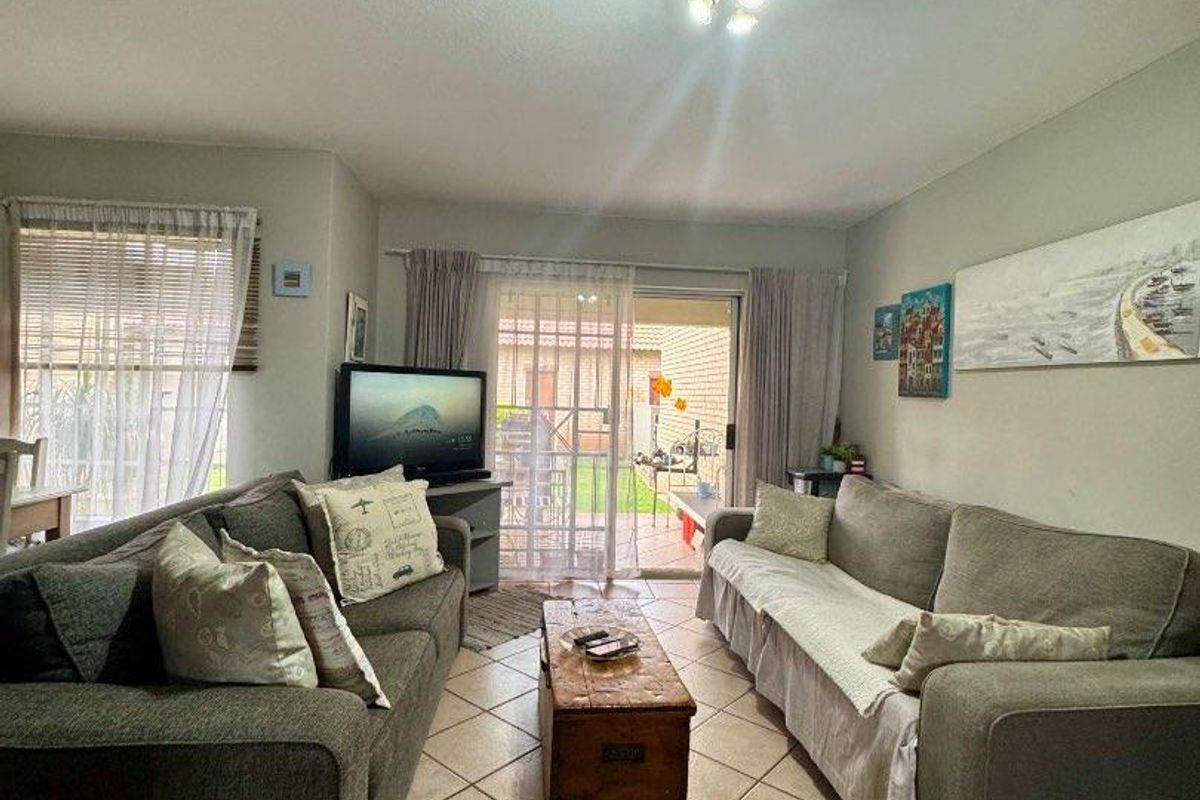 A living room featuring ceramic floor tiles and a sliding glass door providing access to the outdoor area.