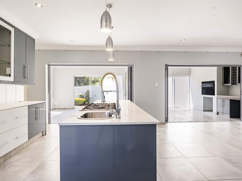 Modern kitchen featuring a central island with a gas hob, sleek cabinetry, and large stacking doors opening to an outdoor area.