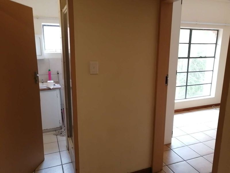 A view from a hallway looking into a bathroom and an adjacent room, featuring tiled flooring and steel-framed windows throughout.