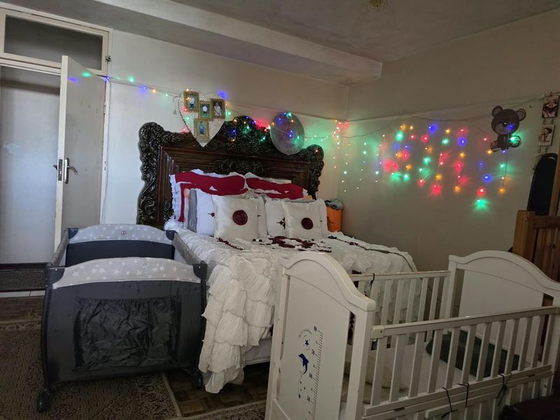 A bedroom featuring a large ornate headboard and an internal door, currently furnished with multiple beds.