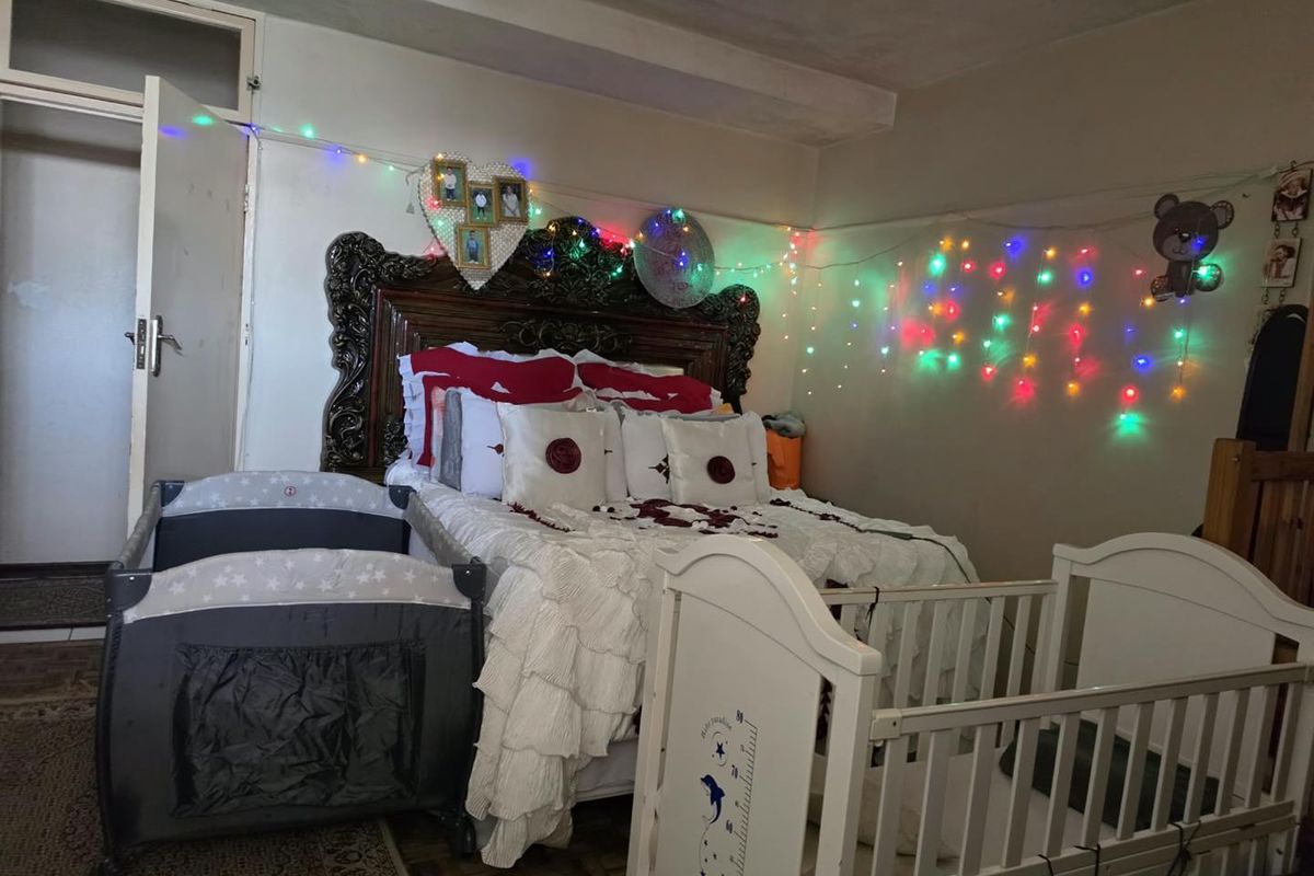 A bedroom featuring a large ornate headboard and an internal door, currently furnished with multiple beds.