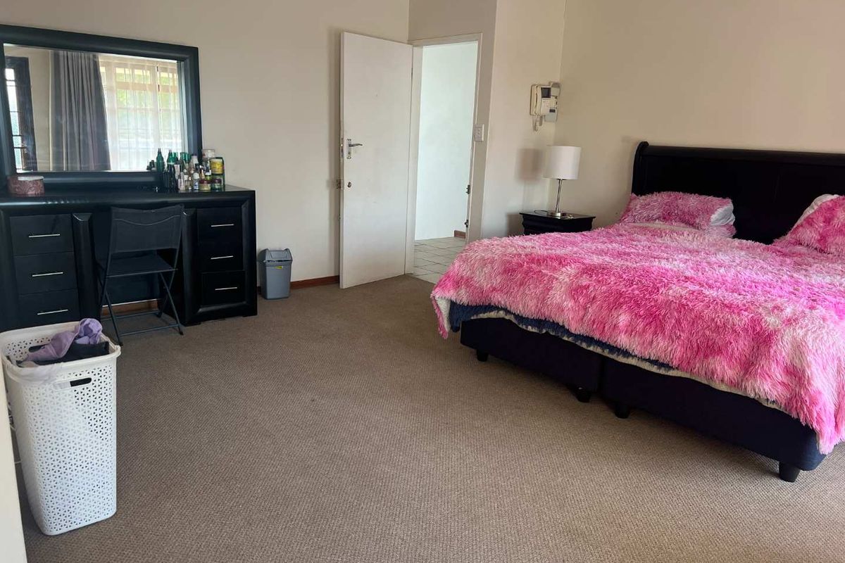 Spacious bedroom featuring neutral wall tones, carpeted flooring, and direct access to an adjoining room.