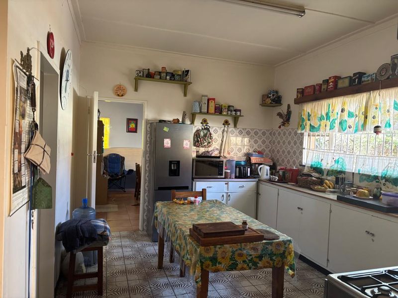 A functional kitchen featuring traditional cabinetry, tiled backsplash, and tiled flooring, offering a practical layout with potential for modern updates.