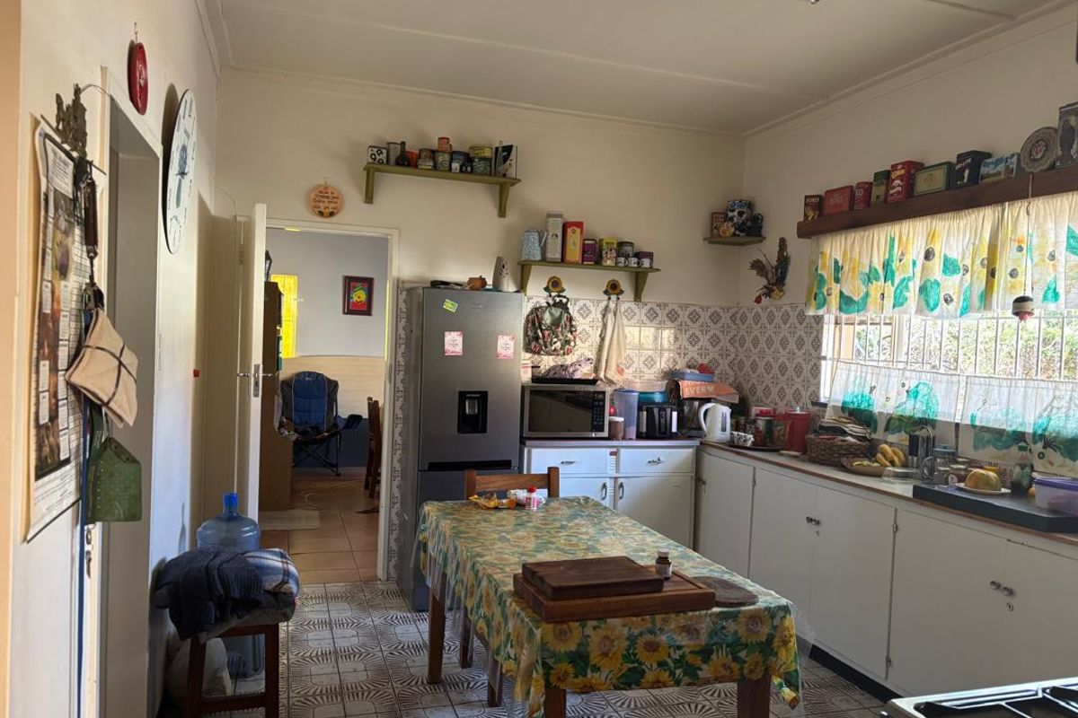A functional kitchen featuring traditional cabinetry, tiled backsplash, and tiled flooring, offering a practical layout with potential for modern updates.