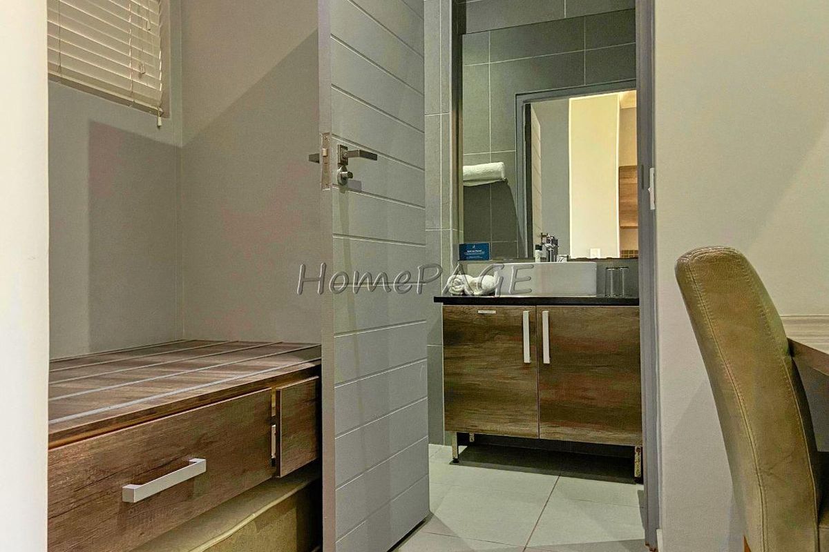 A view into a modern bathroom featuring a vanity with storage cabinetry and tiled walls, accessed via a contemporary interior door.