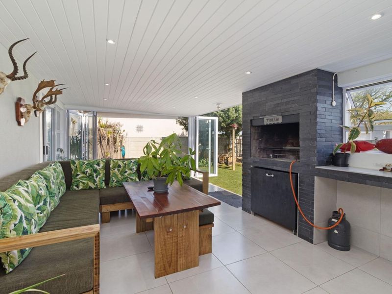 Covered patio area featuring a built-in braai, modern tiled flooring, and bi-fold doors opening to the rear garden.