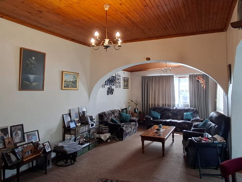 Spacious living area featuring a distinctive timber tongue and groove ceiling and a large arched architectural opening connecting to the adjacent space.