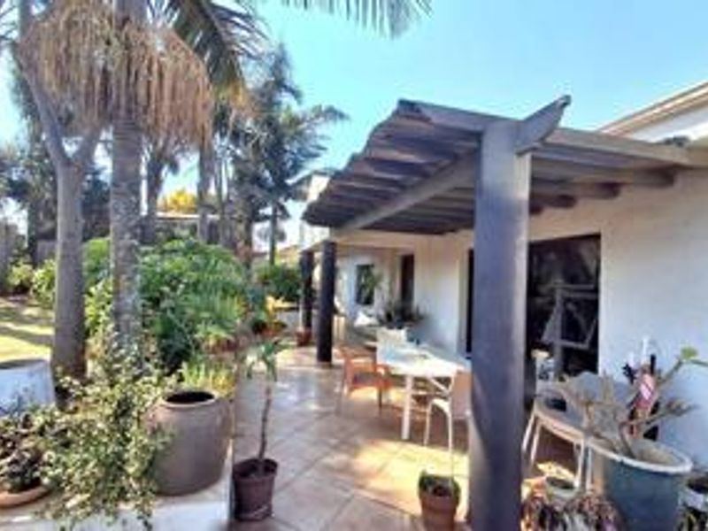 A covered outdoor patio area featuring a timber pergola structure, tiled flooring, and direct access to the home through sliding glass doors.