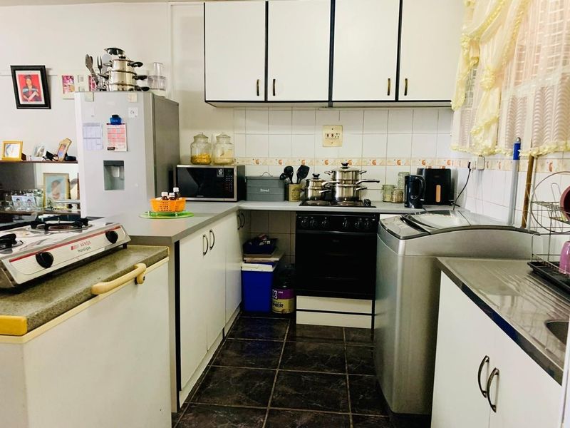 A functional kitchen featuring built-in cabinetry, a tiled backsplash, and integrated cooking appliances, offering a practical layout for daily meal preparation.
