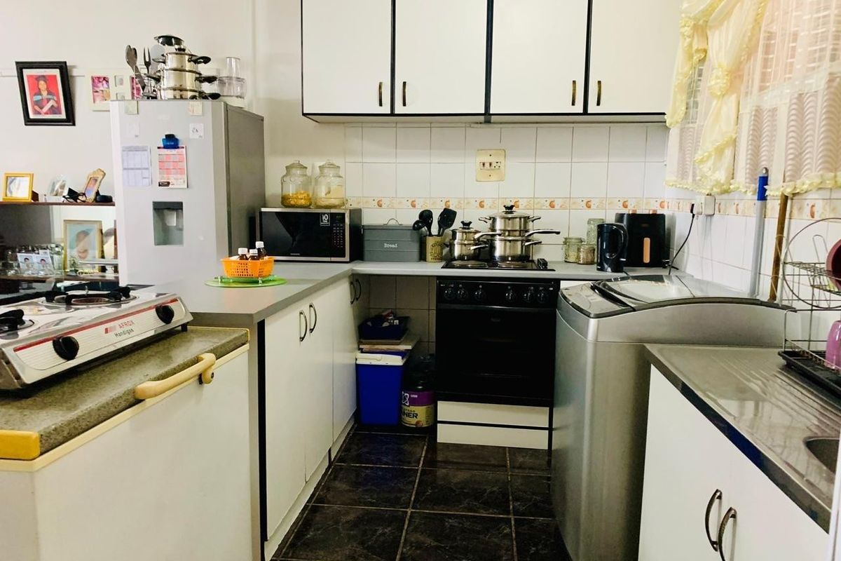 A functional kitchen featuring built-in cabinetry, a tiled backsplash, and integrated cooking appliances, offering a practical layout for daily meal preparation.