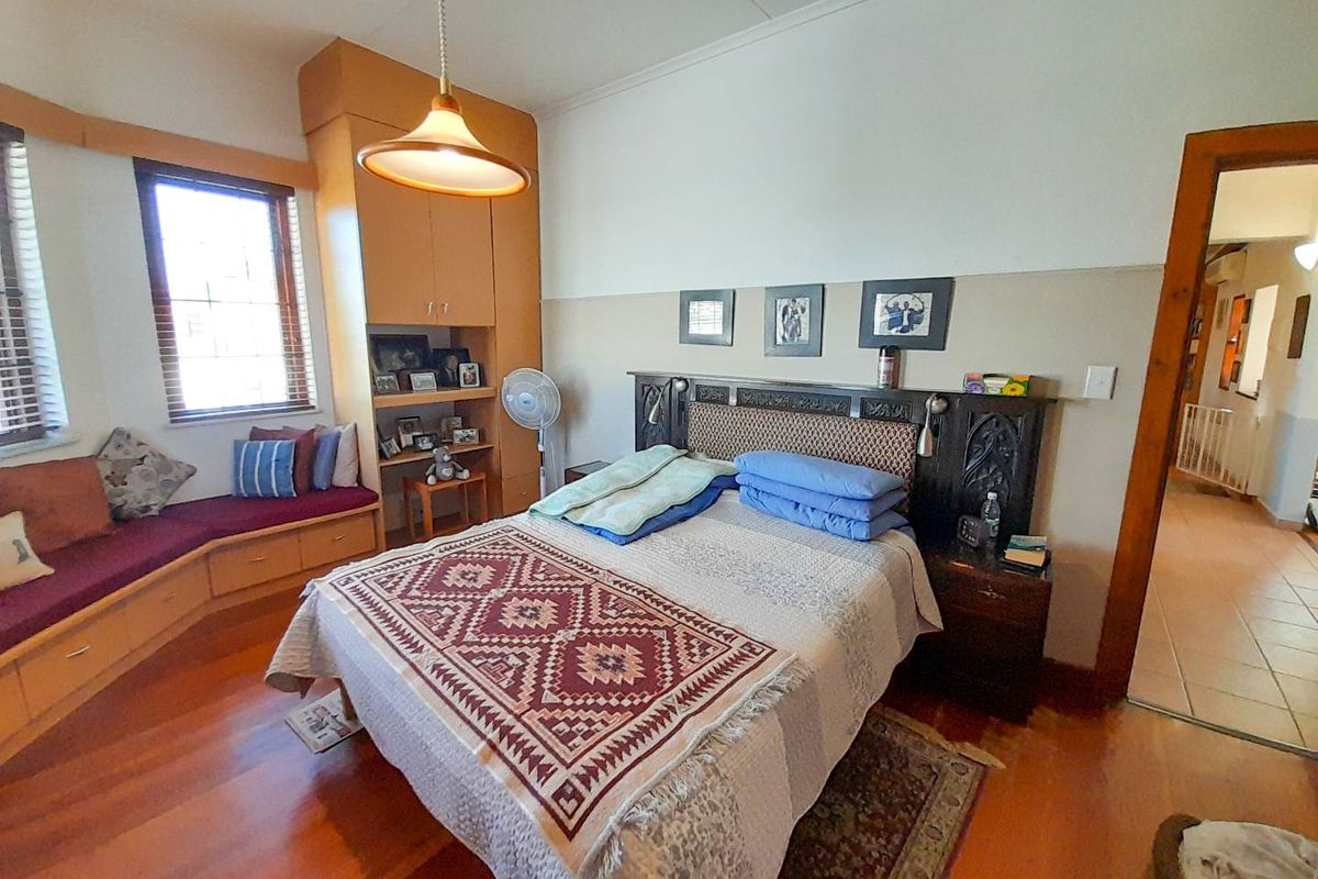 A bedroom featuring built-in wooden cabinetry, a window seat with storage, and timber flooring, offering a functional and classic layout.