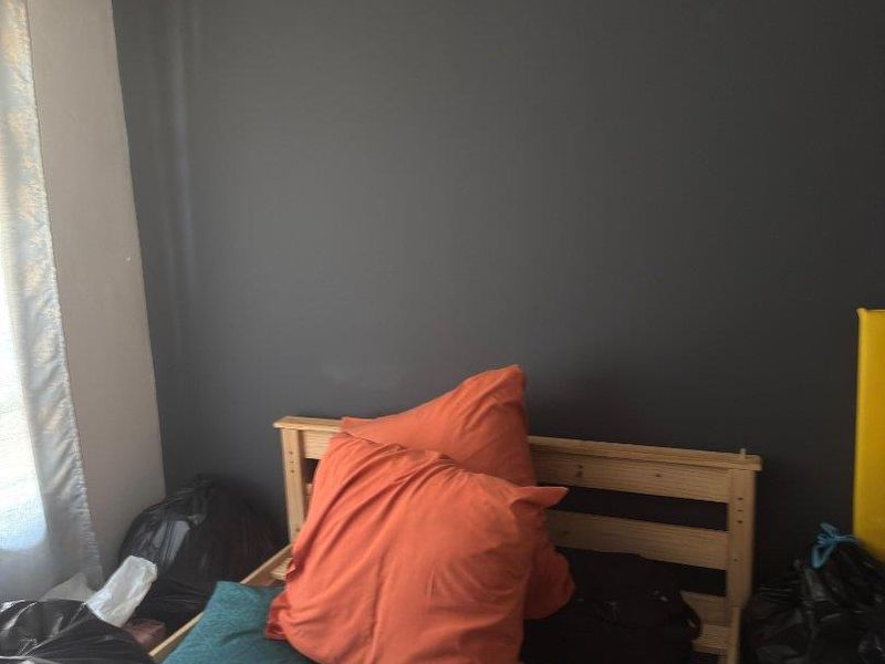 A bedroom featuring a dark accent wall, tiled flooring, and coving detail.