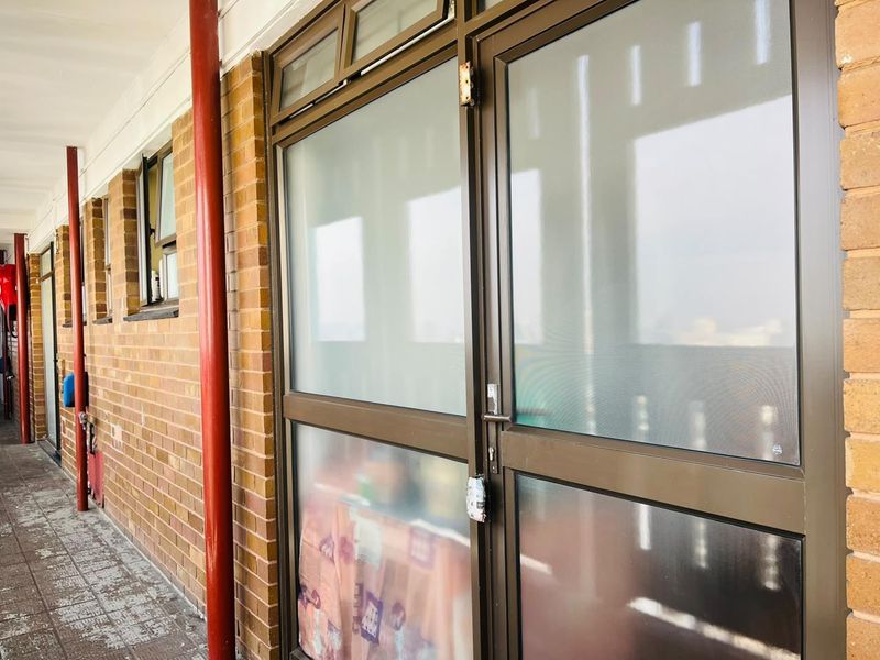 Exterior view of an apartment entrance featuring a brick facade and aluminium-framed glass door with frosted panels.