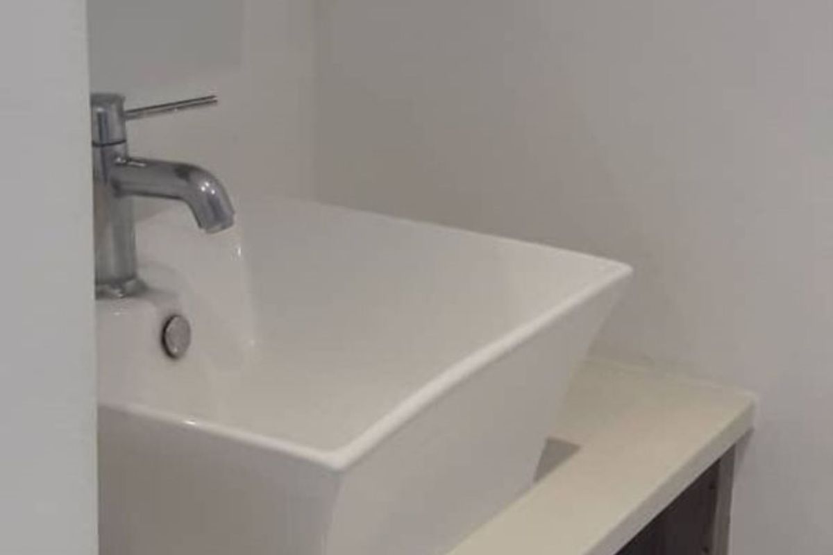 A modern bathroom vanity featuring a white vessel sink with a chrome mixer tap mounted on a sleek countertop.