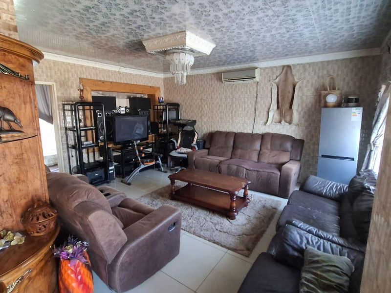 A living room featuring tiled flooring, textured wall coverings, and a decorative ceiling fixture with an integrated split-system air conditioner.