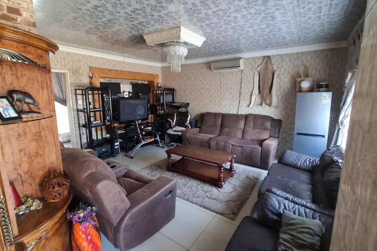 A living room featuring tiled flooring, textured wall coverings, and a decorative ceiling fixture with an integrated split-system air conditioner.