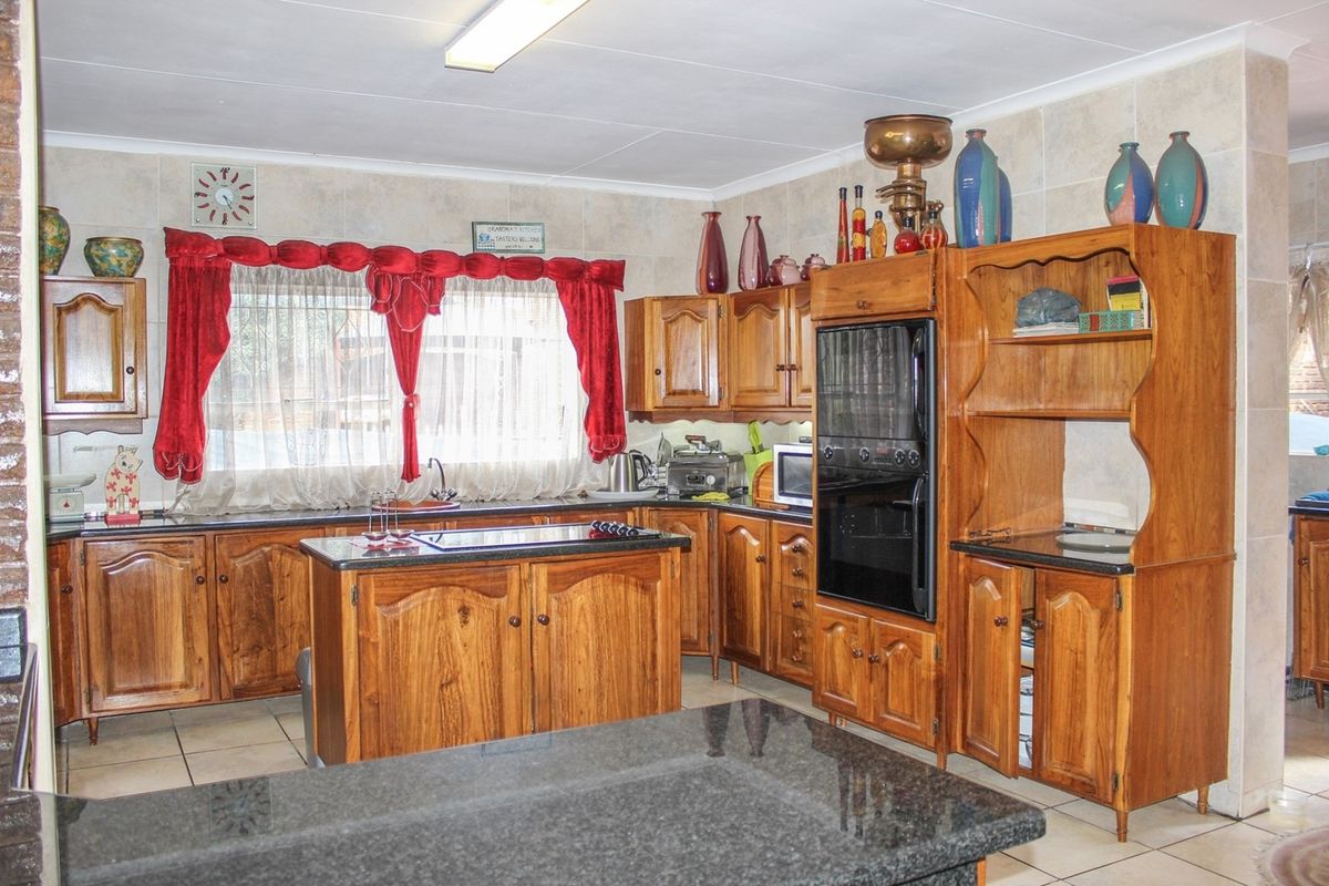 A traditional kitchen featuring solid wood cabinetry, dark granite countertops, a central island, and a built-in eye-level oven.
