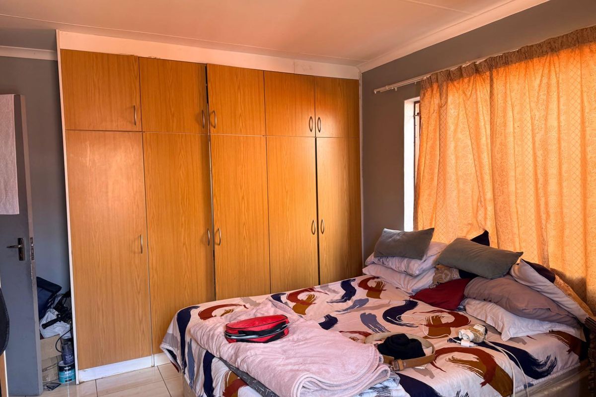 A bedroom featuring built-in wooden cupboards and tiled flooring, providing functional storage space.