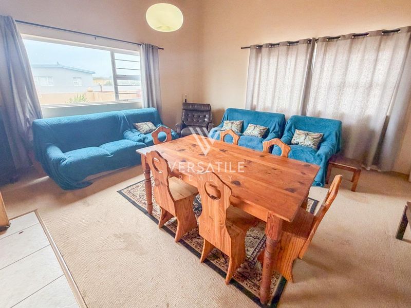 A spacious living and dining area featuring carpeted flooring and large windows, offering a functional layout ready for modern updates.