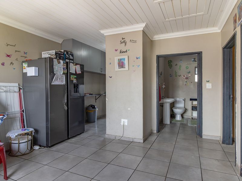 Open plan living area featuring tiled floors and a tongue and groove ceiling, with an adjacent bathroom containing a pedestal sink and toilet.