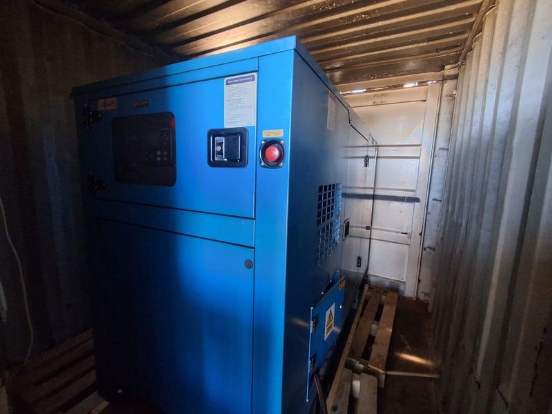A secure industrial generator housed within a dedicated shipping container enclosure, providing reliable backup power infrastructure for the property.