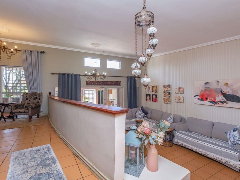 Spacious living area featuring ceramic tile flooring, a central partition wall, decorative pendant lighting, and access to an outdoor area through sliding glass doors.