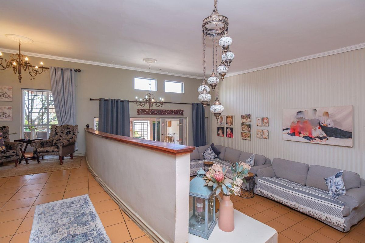 Spacious living area featuring ceramic tile flooring, a central partition wall, decorative pendant lighting, and access to an outdoor area through sliding glass doors.