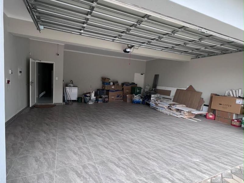 Spacious double garage featuring modern grey tiled flooring and a functional sectional overhead door with direct internal access.