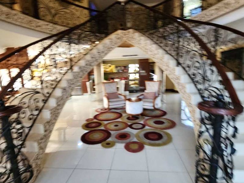 Grand entrance foyer featuring a sweeping staircase with ornate wrought iron balustrades, polished tile flooring, and a prominent crystal chandelier.