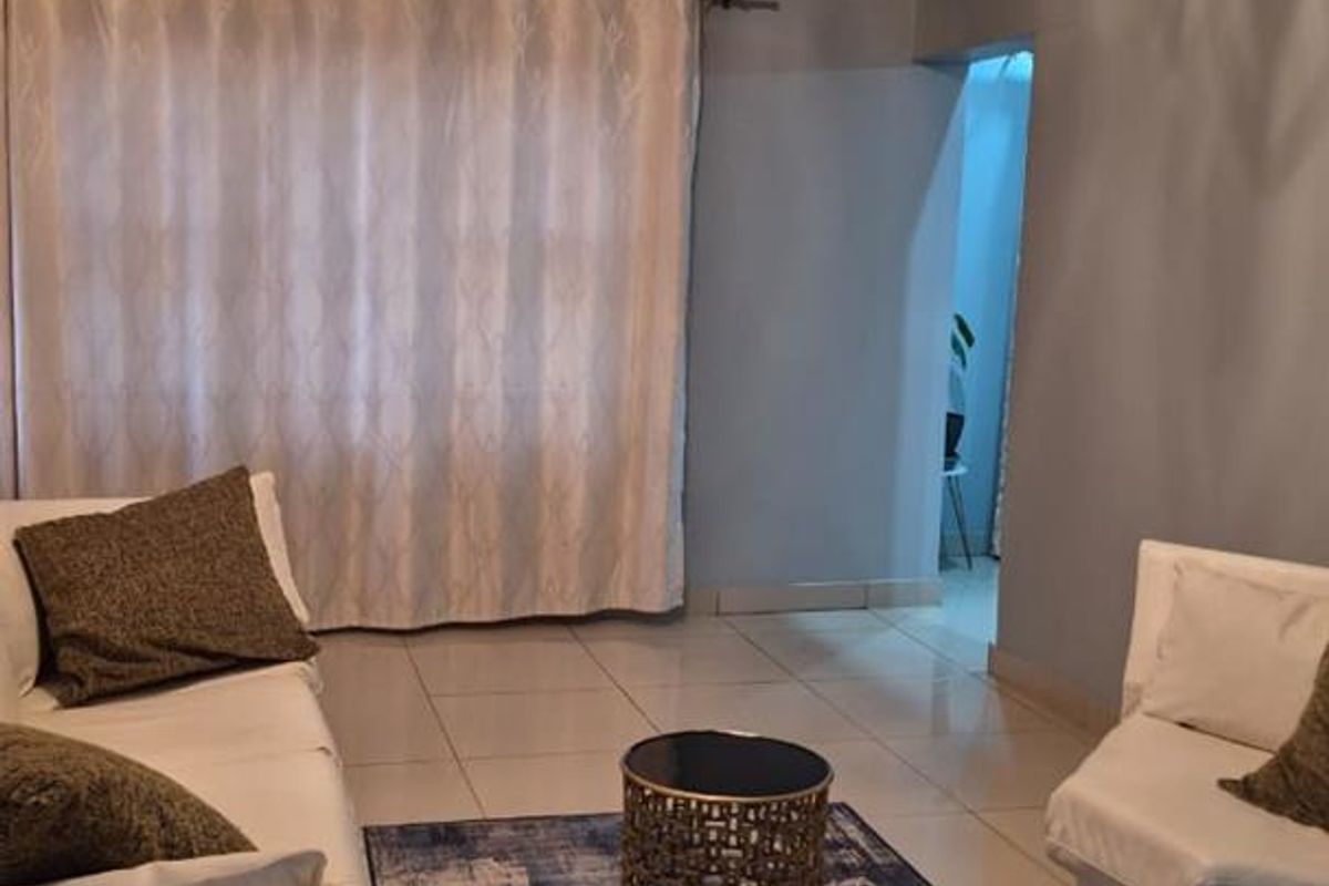 A living room featuring tiled flooring, a textured ceiling with a decorative light fixture, and a window with a curtain rod.