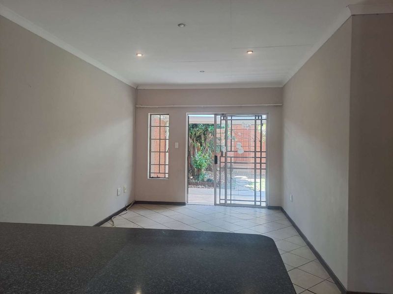 An open-plan living area featuring tiled flooring, recessed lighting, and a sliding door providing direct access to the rear garden.
