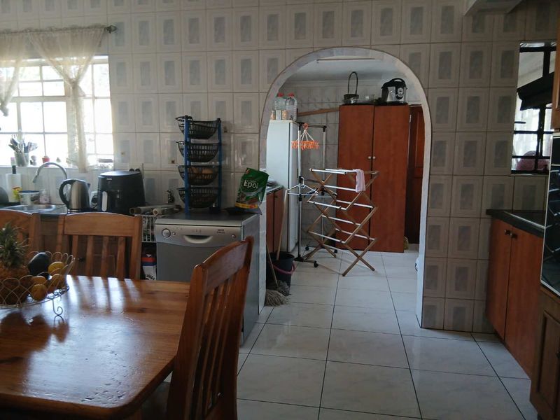 A functional kitchen area featuring tiled walls and flooring, connected to an adjacent utility space through a classic arched doorway.