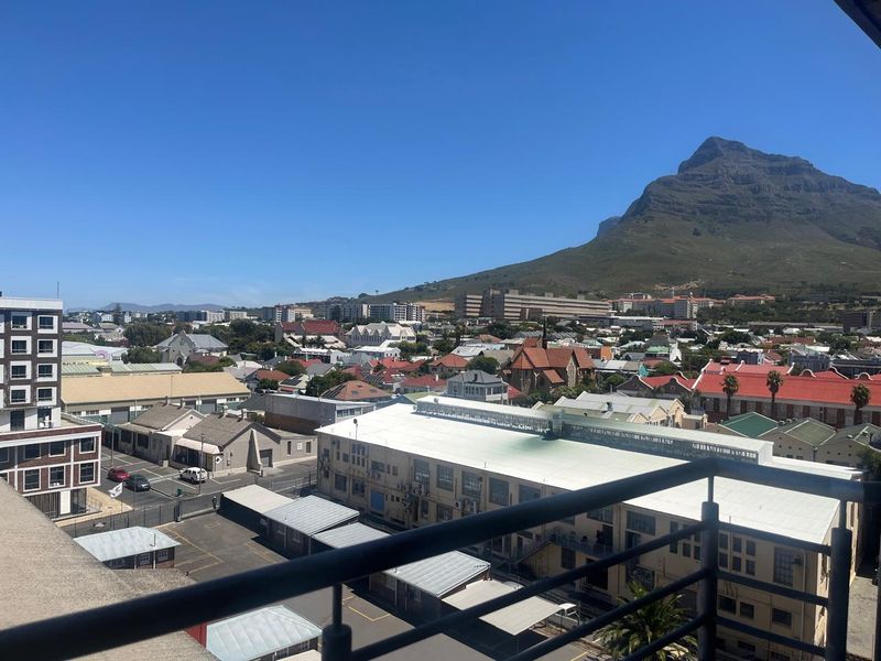 Elevated urban view overlooking the surrounding neighbourhood and mountain landscape, captured from a balcony with a metal railing.