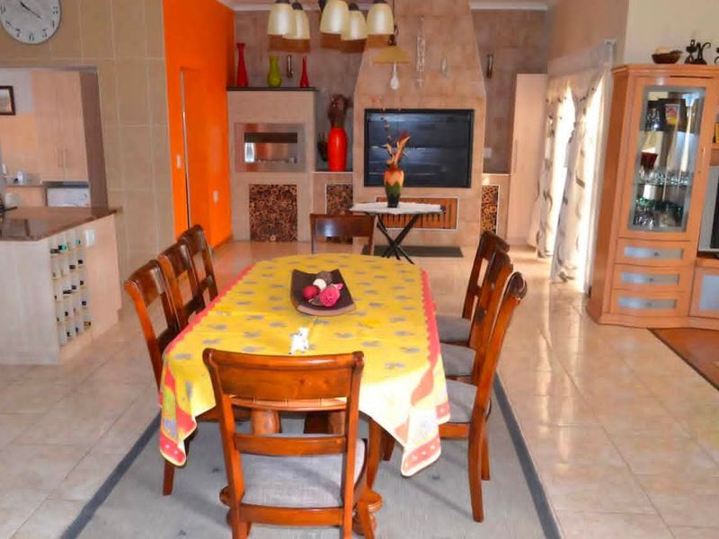 Open plan dining and kitchen area featuring a built-in fireplace, tiled flooring, and granite kitchen countertops.