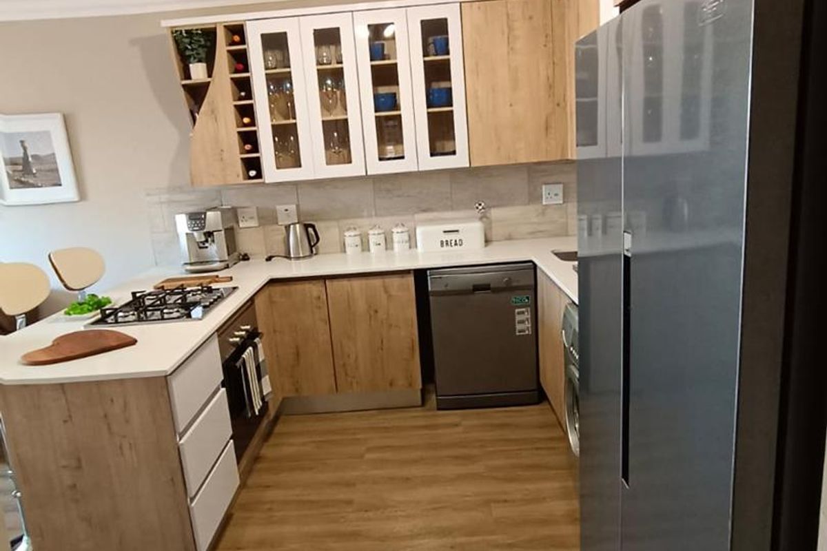 Modern kitchen featuring wood-grain cabinetry, stone countertops, integrated gas hob, built-in oven, and light wood-look flooring in an open-plan layout.